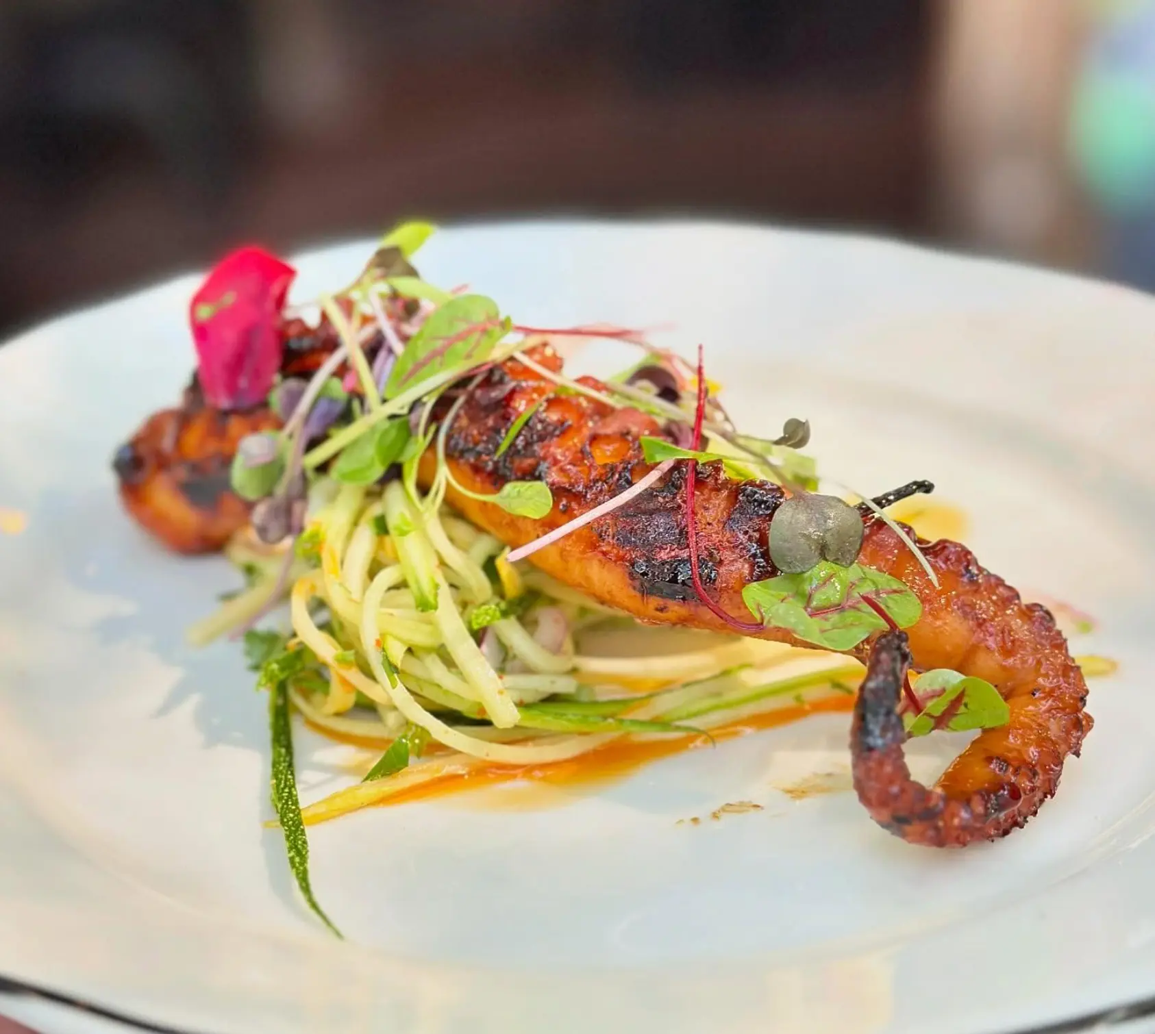 Grilled octopus with zucchini, microgreens and savory sauce.