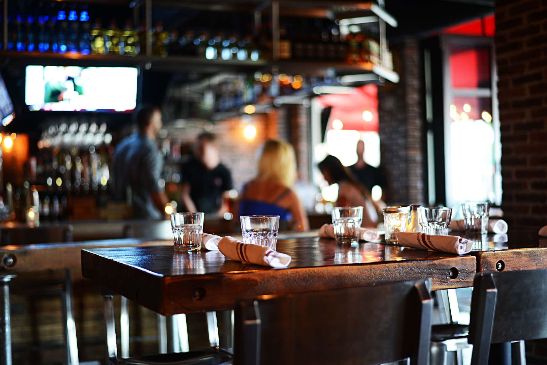 Park Tavern dining room with a set table and guests at the bar.