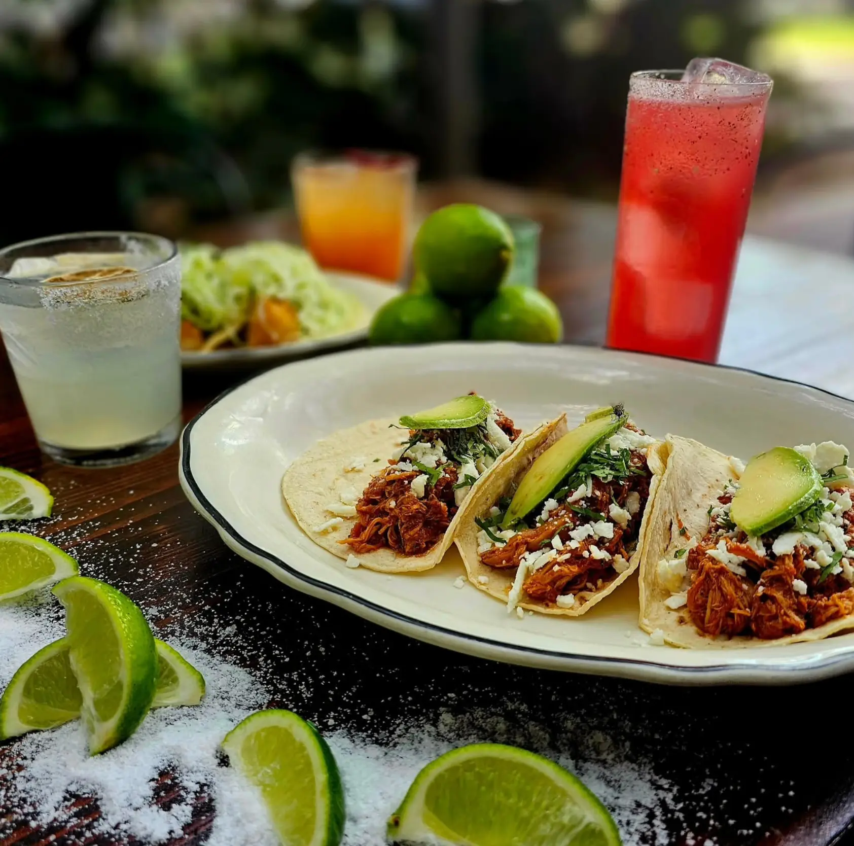 Chicken tacos with avocado, herbs, cheese and colorful cocktails.